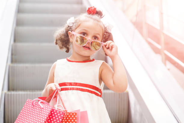 menina na escada rolante no shopping com compras - escalator child shopping mall little girls - fotografias e filmes do acervo