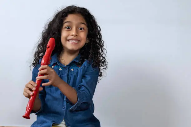 Latin American girl smiling and happy holding her soprano recorder