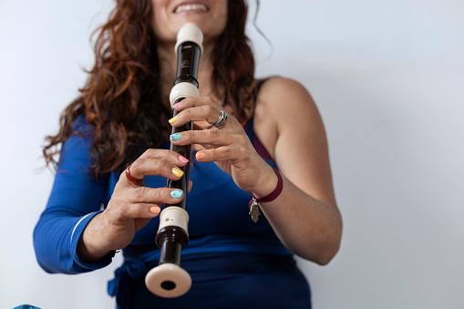Latin American music teacher playing an alto recorder.