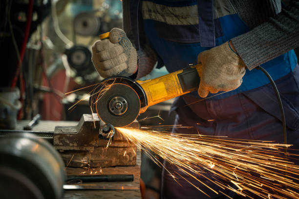 istock Locksmith in special clothes and goggles works in production. Metal processing with angle grinder. Sparks in metalworking 1402975734