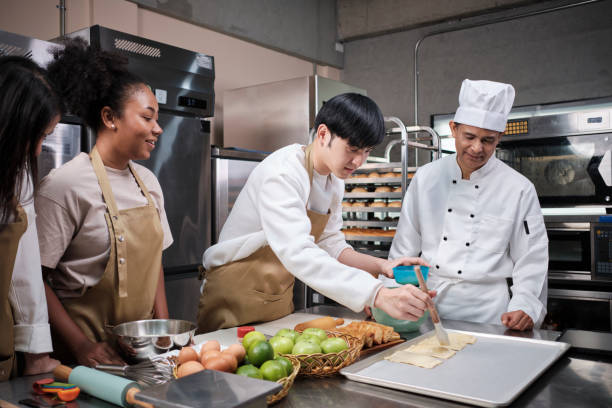 istock Senior chef teaches cooking students to prepare pastry dough for fruit pies. 1402976855