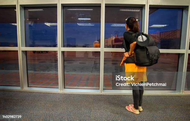Young Woman Is Standing Near Window At The Airport And Watching Plane Before Departure She Is Standing Looking At Airplane Taking Off And Carrying Luggagetravel And Lifestyle Concept Stock Photo - Download Image Now