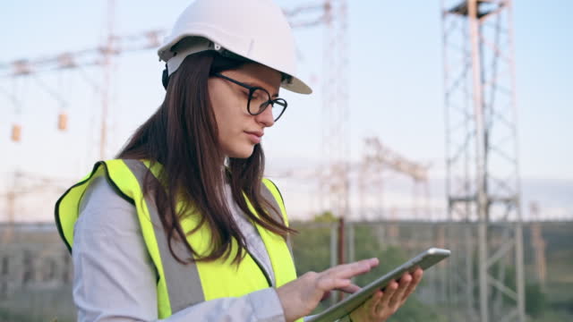 Young female engineer using digital tablet at power plant.