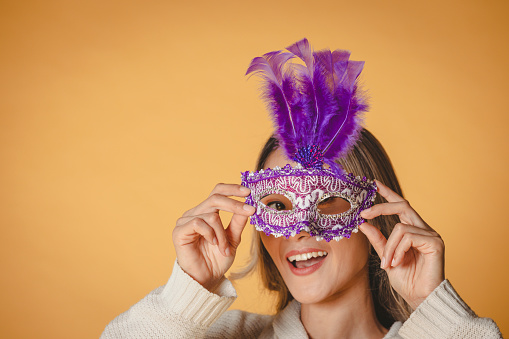 Portrait of woman with carnival mask on yellow background.art culture and entertainment