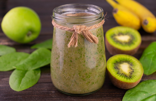 Smoothie with spinach banana and kiwi and apple in a jar.