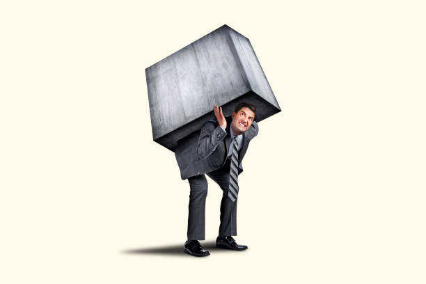 istock Man Struggles To Carry Large Concrete Block On His Back 1402990552