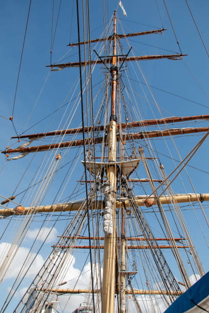 Ropes and the mast to control the sails, details of the device of the yacht, sailing ship equipment against the blue sky, vertical view Ropes and the mast to control the sails, details of the device of the yacht, sailing ship equipment against the blue sky, vertical view sailboat mast stock pictures, royalty-free photos & images