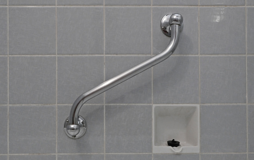 Close-up of a bathroom from the 70s. A grab bar is used for seniors to use the bathtub.