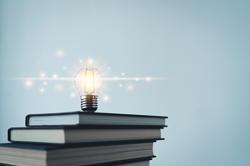 Glowing lightbulb or bright lamp with book or textbook. Skill improvement for student or businessperson. Studying and training course online at home. Business success idea, education learning concept