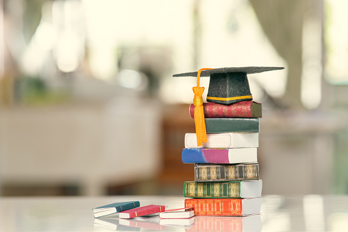 Graduate study abroad program to broaden learner's world view, education concept Graduation cap, foreign books on a table. The image depicting students attempt to study from a distance or learning from home.