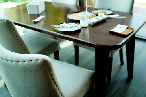 Close up of a small table and four chairs in an eat in kitchen with a tile floor, a rug, plant, and placemats.