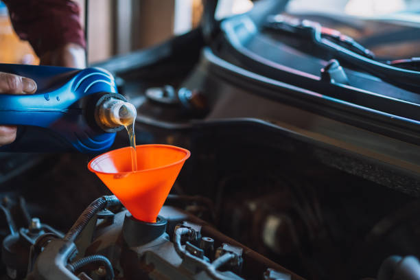The mechanic pours new oil into the engine using funnel stock photo