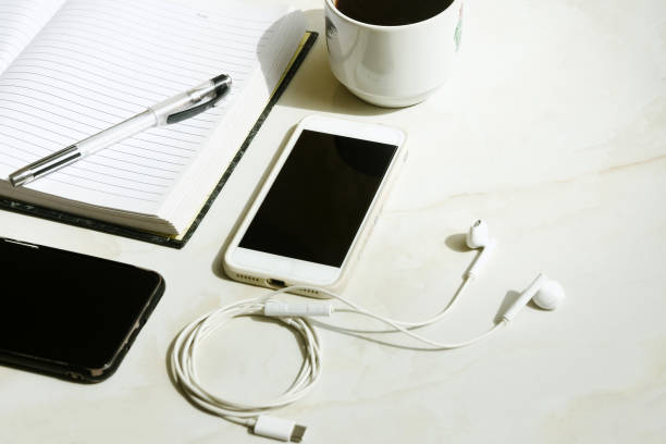 istock Side view white cable earphones on white background with smartphone, black coffee and a notebook 1402999627