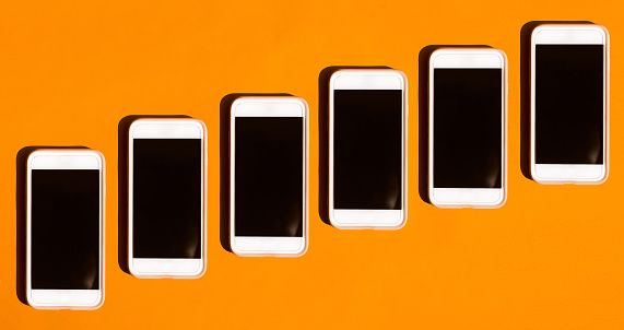 Top-view of mobile phone or smartphone blank screen on colored orange background