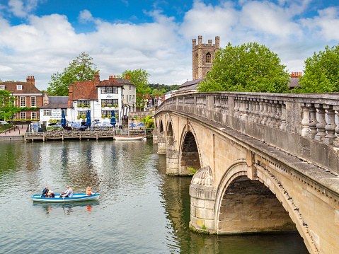 4 June 2019: Henley on Thames, UK - Henley Bridge and the River Thames, with The Angel riverside pub and restaurant, and family in rowing boat on river.