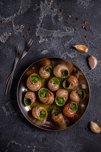 Bourgogne Escargot Snails with herb garlic oil in a metal plate.
