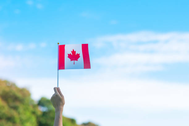 istock hand holding Canada flag on blue sky background. Canada Day  and happy celebration concepts 1403004988