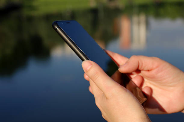 istock Smartphone in female hands close up on lake background 1403005055