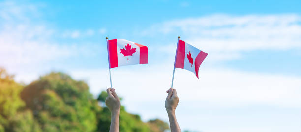 istock hand holding Canada flag on blue sky background. Canada Day  and happy celebration concepts 1403005600