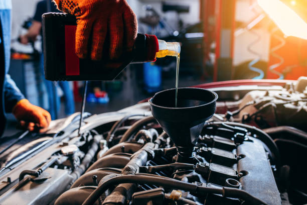 nahaufnahme der hand des automechanikers, der motoröl in einem modernen automobilmotor in der autoreparaturwerkstatt ersetzt und gießt. - equipment conformity car transportation stock-fotos und bilder