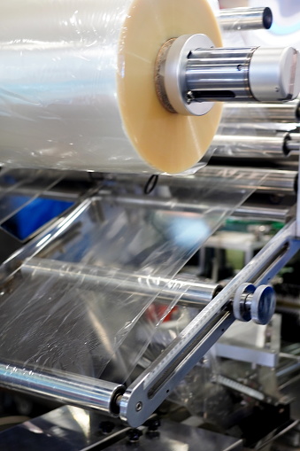 Close-up Roll of plastic packaging film on the automatic packing machine in food product factory