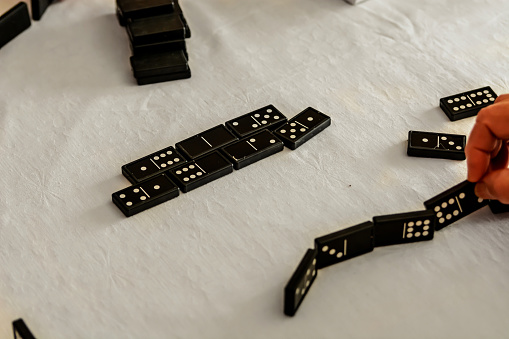 In a social center, a group of active seniors are enjoying playing dominoes.