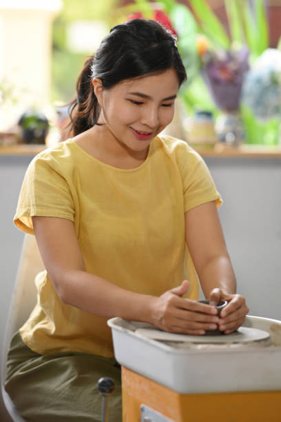 istock Concentrated woman is creating handmade tableware in pottery workshop. Pottery working, handmade clay products and creative skills. 1403011648