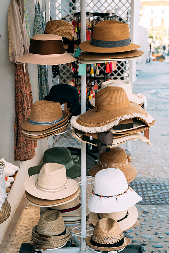 View of many different straw hats displayed for sale in a store in the street. Shop and tourism concept.