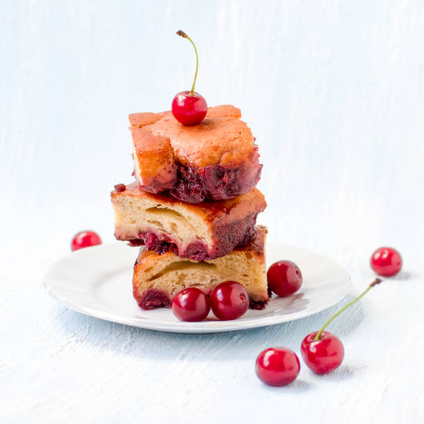 A piece of cherry pie on a plate with cherries in the background