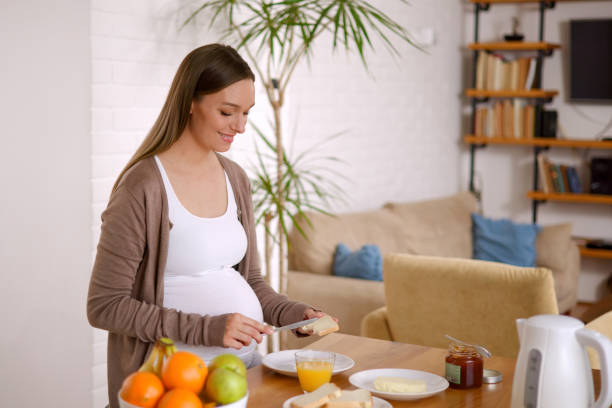 Beautiful young pregnant woman eating a healthy breakfast at home stock photo