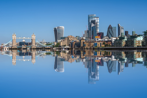 London cityscape with reflection from the River Thames against blue cloudless sky