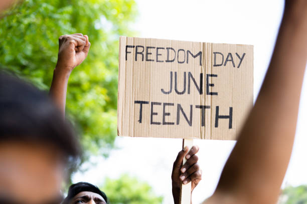 concept of juneteenth freedom day march showing by close up protesting hands sign board - concept of activism, justice and demonstration - juneteenth stockfoto's en -beelden