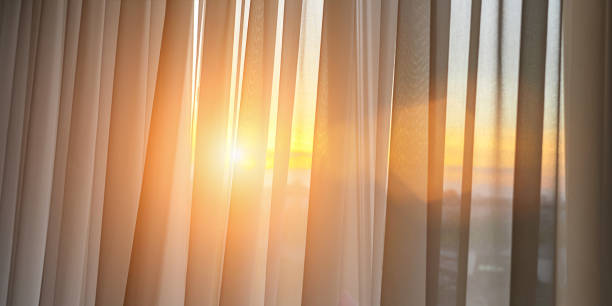 istock Bright sunlight shines through transparent silk curtain hanging at room. 1403021599