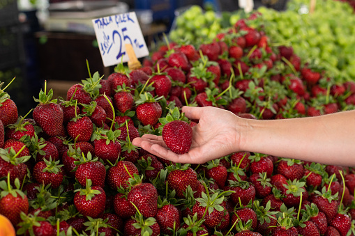 Many fresh strawberries in boxes for sale at a fruit market outdoors. Top view. Healthy food.