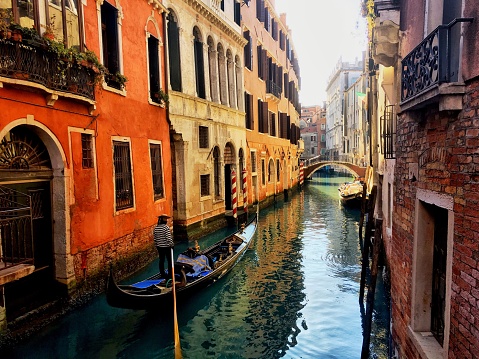 Tourists riding a gondola through the canals of Venice, Italy