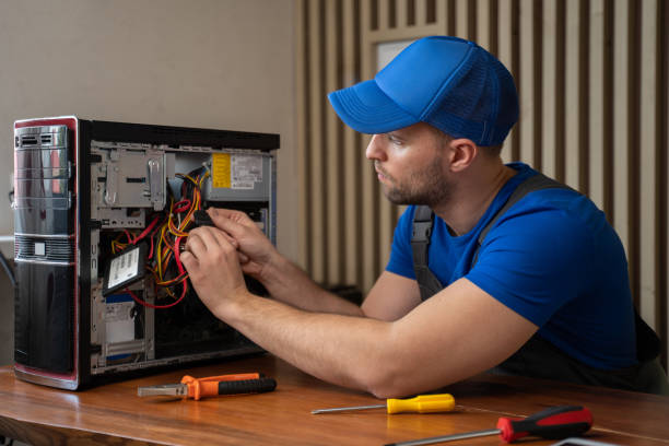 Man in t-shirt repairs computer system unit with screwdriver stock photo