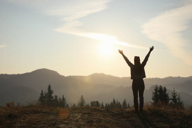 silhouette de femme au lever du soleil dans les montagnes, vue arrière. espace pour le texte - hiking young women outdoors t shirt photos et images de collection