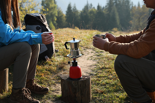 Young couple drinking coffee near camping tents outdoors, closeup