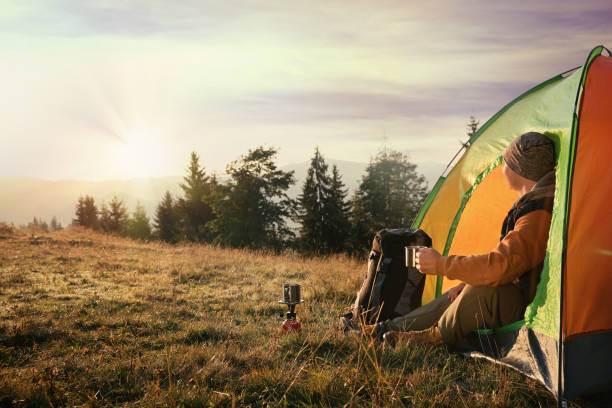 istock Man with cup of hot drink in camping tent. Space for text 1403027439