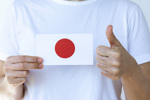 Hand is showing Japanese flag to camera.