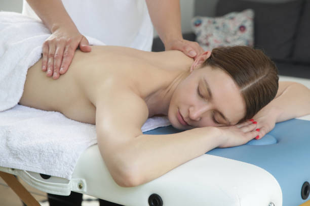 istock Mobile massage service. Young woman having soft shooting relax massage at home. 1403027736