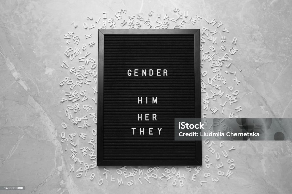 Black board with words Gender, Him, Her, They and letters on grey marble table, flat lay Pronoun Stock Photo