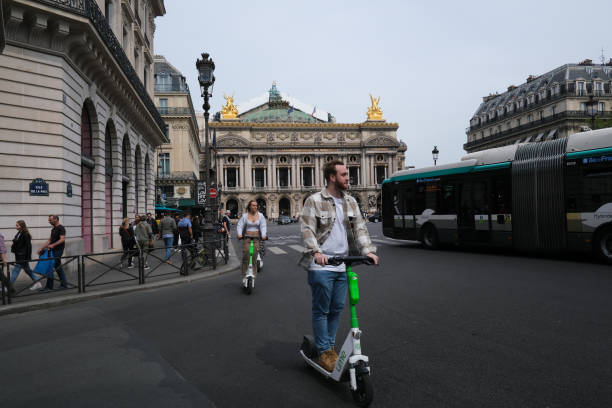 People ride electric scooters People ride electric scooters  in front of Opera in Paris, France on APril 23, 2022. lime scooter stock pictures, royalty-free photos & images