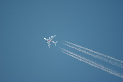 High Flying emirates airline with vapor trails contrails chem trails, clear blue sky june 2022 the netherlands