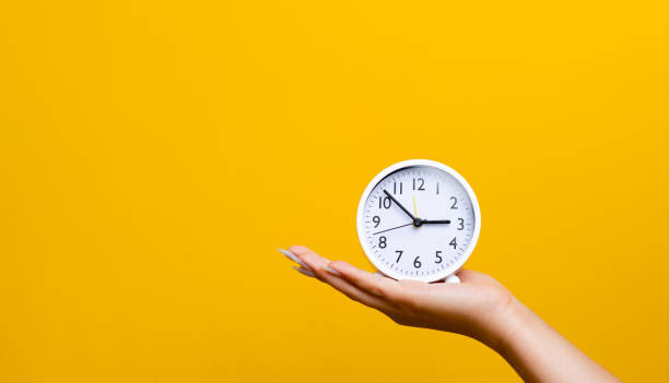 istock hand and white alarm clock On hand 1403036115