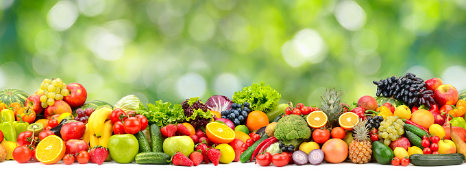 Wide horizontal seamless pattern of vegetables and fruits on green blurred background