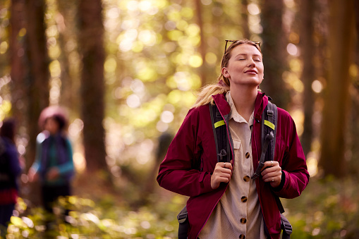 Woman Closing Eyes Enjoying Peace As Group Of Female Friends On Holiday Hike Through Woods Together