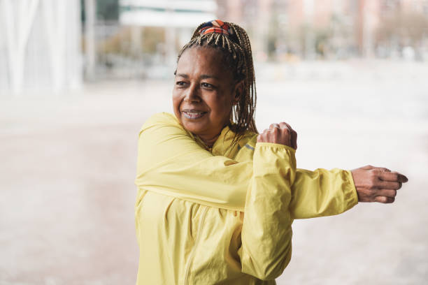 donna africana senior che si allunga durante la routine di allenamento all'aperto - focus sul viso - african ethnicity exercising muscular build healthy lifestyle foto e immagini stock