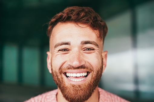 Young happy man smiling on camera outdoor - Focus on face