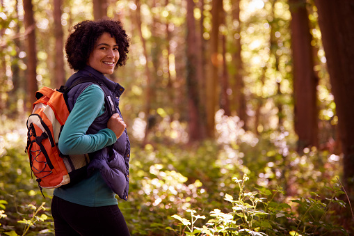 Portrait Of Smiling Woman On Camping Holiday Hiking Through Woods And Enjoying Nature